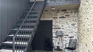 Eine Treppe mit Metallgeländern führt zu einem Balkon mit Steinmauern und Blick auf den Himmel.
