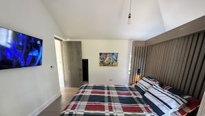 Ein Schlafzimmer mit einem großen Bett, einem flachbildfernseher an der Wand und einem hölzernen Kopfteil.