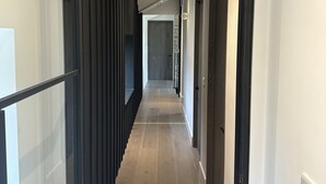 Ein moderner Flur mit Holzboden, schwarzen Glastüren und einer Wandleuchte.
