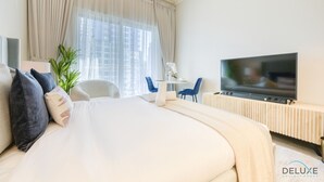 Ein modernes Hotelzimmer mit einem großen Bett, einem Fernseher, einem kleinen Tisch mit Stühlen und einer Zimmerpflanze.