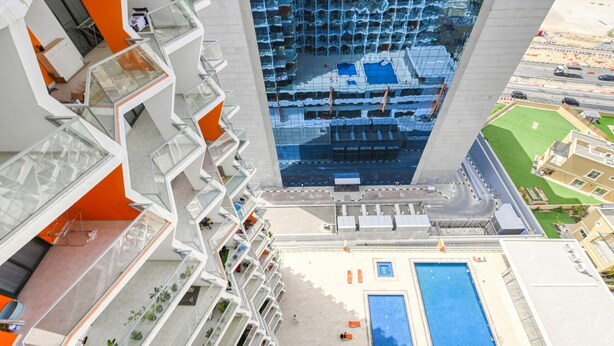 A high-rise hotel with multiple balconies, a rooftop pool, and a view of the surrounding cityscape. - Urban 1BR at Binghatti Stars Dubai Silicon Oasis by Deluxe Holiday Homes (Dubai)