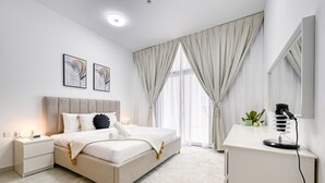 A modern bedroom with a bed, bedside tables, a desk, and a mirror. - Urban 1BR at Binghatti Stars Dubai Silicon Oasis by Deluxe Holiday Homes (Dubai)