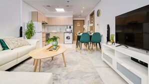 A modern living room with a sofa, coffee table, TV, and dining area with chairs. - Urban 1BR at Binghatti Stars Dubai Silicon Oasis by Deluxe Holiday Homes (Dubai)