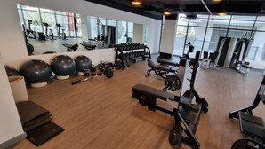 A gym with exercise equipment, a bench, and a mirror. - Urban 1BR at Binghatti Stars Dubai Silicon Oasis by Deluxe Holiday Homes (Dubai)