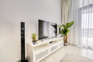 Uma sala de estar moderna com televisão de tela plana, unidade de armazenamento branca e um vaso com planta.