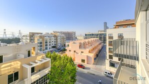 Un quartier résidentiel urbain moderne, avec des immeubles à plusieurs étages, un ciel dégagé et quelques véhicules dans la rue.