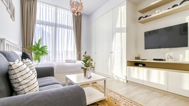 Un salon moderne avec un canapé gris, une table basse blanche et un téléviseur à écran plat fixé au mur.