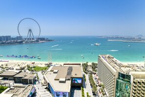 A coastal cityscape with a prominent Ferris wheel, beachfront, and modern buildings.