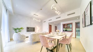 Un comedor moderno con una mesa blanca dispuesta para cuatro personas, rodeada de sillas tapizadas en rosa.
