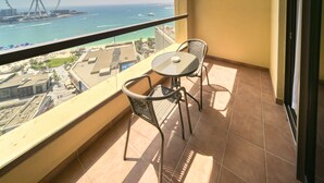 Un balcón con una mesa y dos sillas, con vista a una playa y una noria.