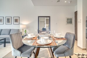 Uma sala de jantar moderna com mesa de vidro, cadeiras estofadas cinzentas e uma ilha central com uma tigela.