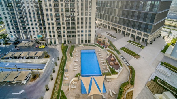 A high-rise building with a rooftop pool and surrounding amenities. - Graceful 1BR at Park Heights Dubai Hills MBR City by Deluxe Holiday Homes (Dubai)