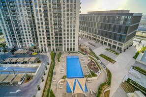 Um edifício alto com piscina no terraço e comodidades nos arredores.