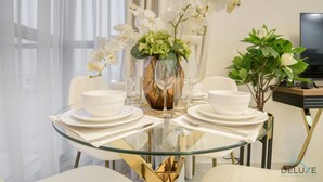 Ein Esstisch mit weißen Tellern, Schüsseln und einer Vase mit weißen Orchideen.