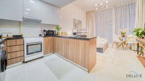 Eine moderne Küche mit weißen Schränken, einem eingebauten Backofen und einem Essbereich mit weißem Tisch und Stühlen.