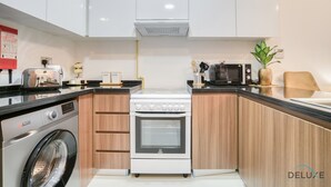 Eine moderne Küche mit weißen Schränken, Backofen, Mikrowelle und Waschmaschine.