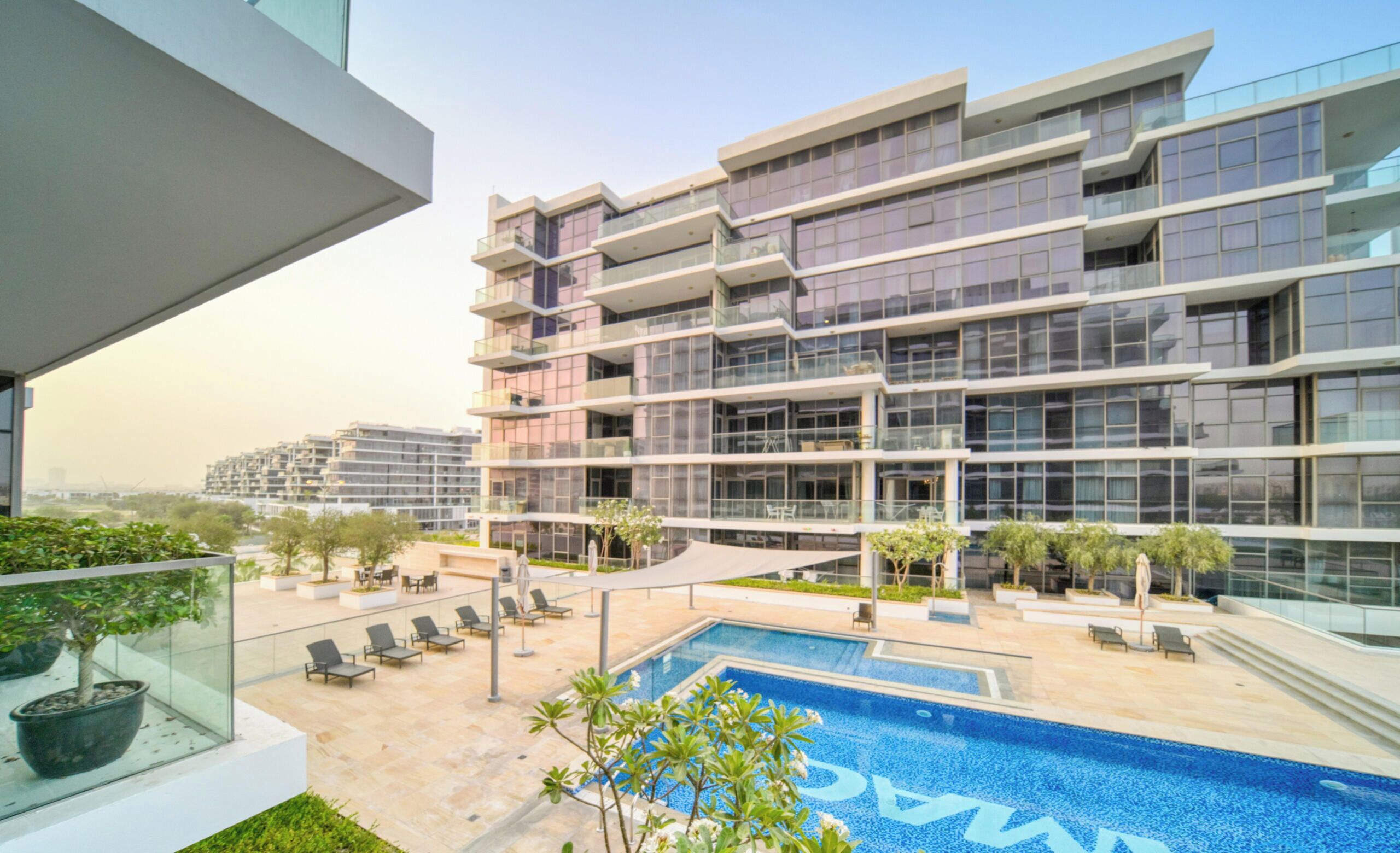 A modern building with a rooftop pool, glass balconies, and outdoor seating areas.
