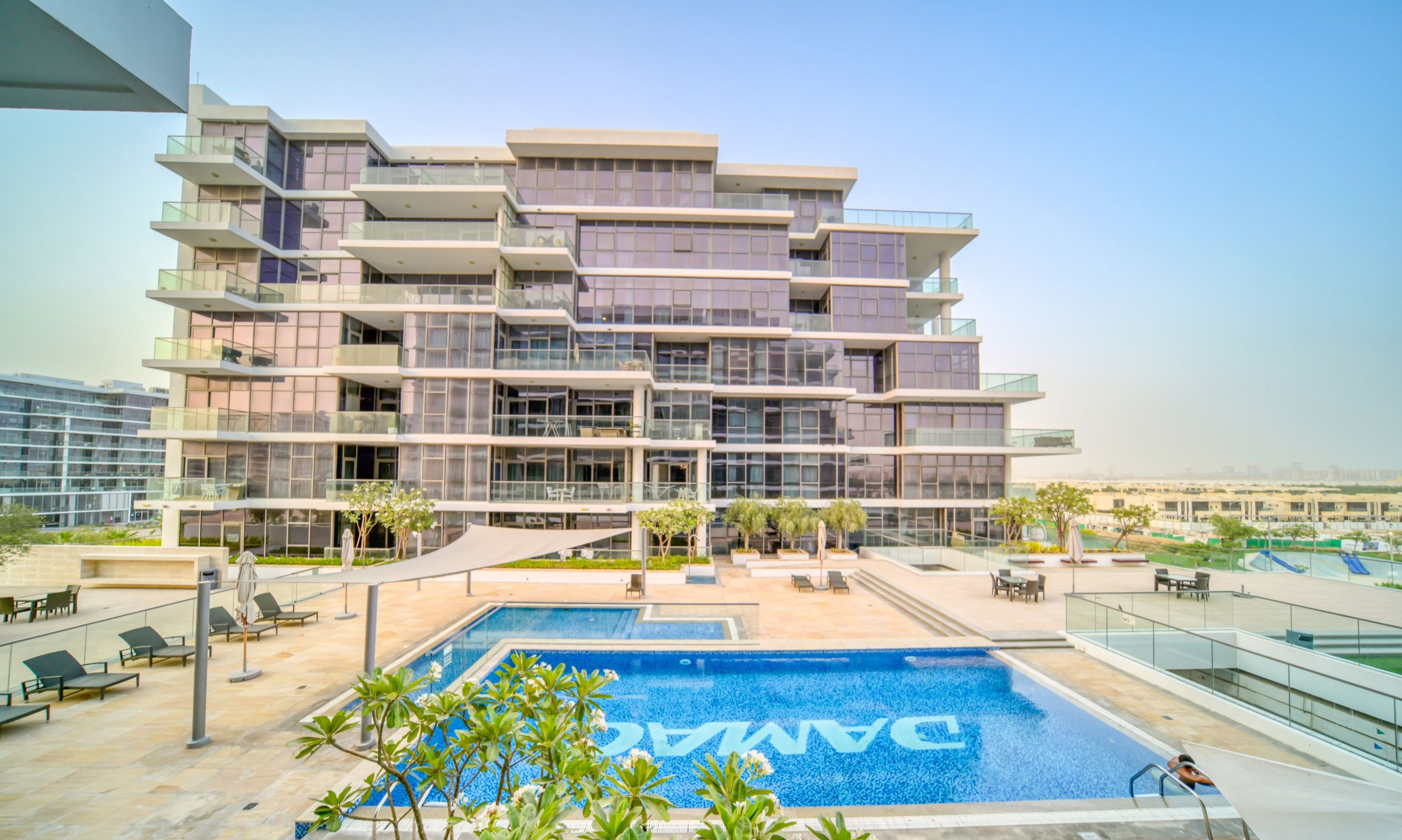 A modern multi-story hotel with a rooftop pool area.