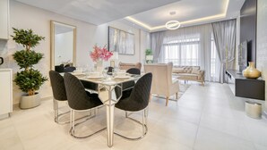 Uma área de jantar moderna com uma mesa de vidro, cadeiras pretas e um vaso de planta.