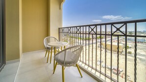 Varanda com duas cadeiras e uma mesa, com vista para um canteiro de obras.