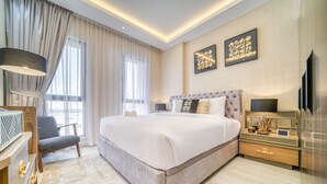 Um quarto espaçoso com uma cama grande, uma mesinha de cabeceira, uma cadeira e uma televisão.
