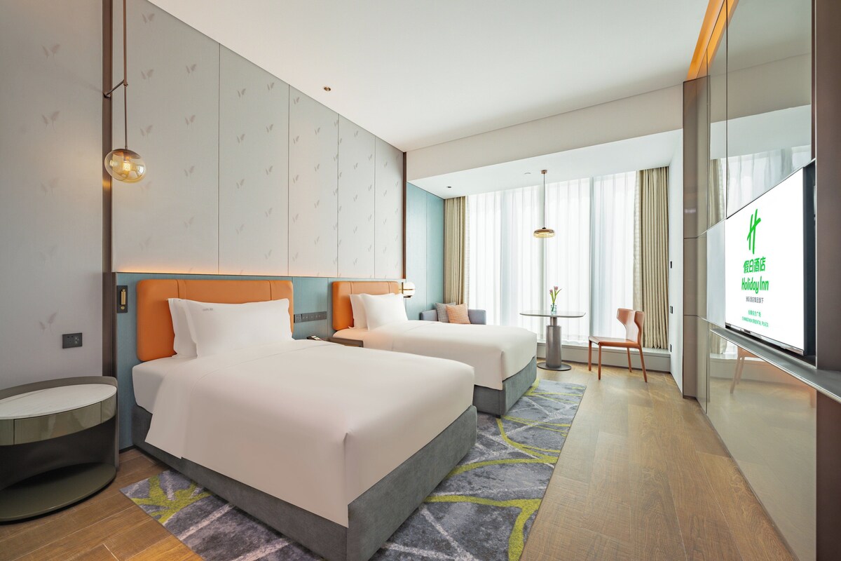 Une chambre d’hôtel avec deux lits, une petite table, une chaise et un téléviseur.