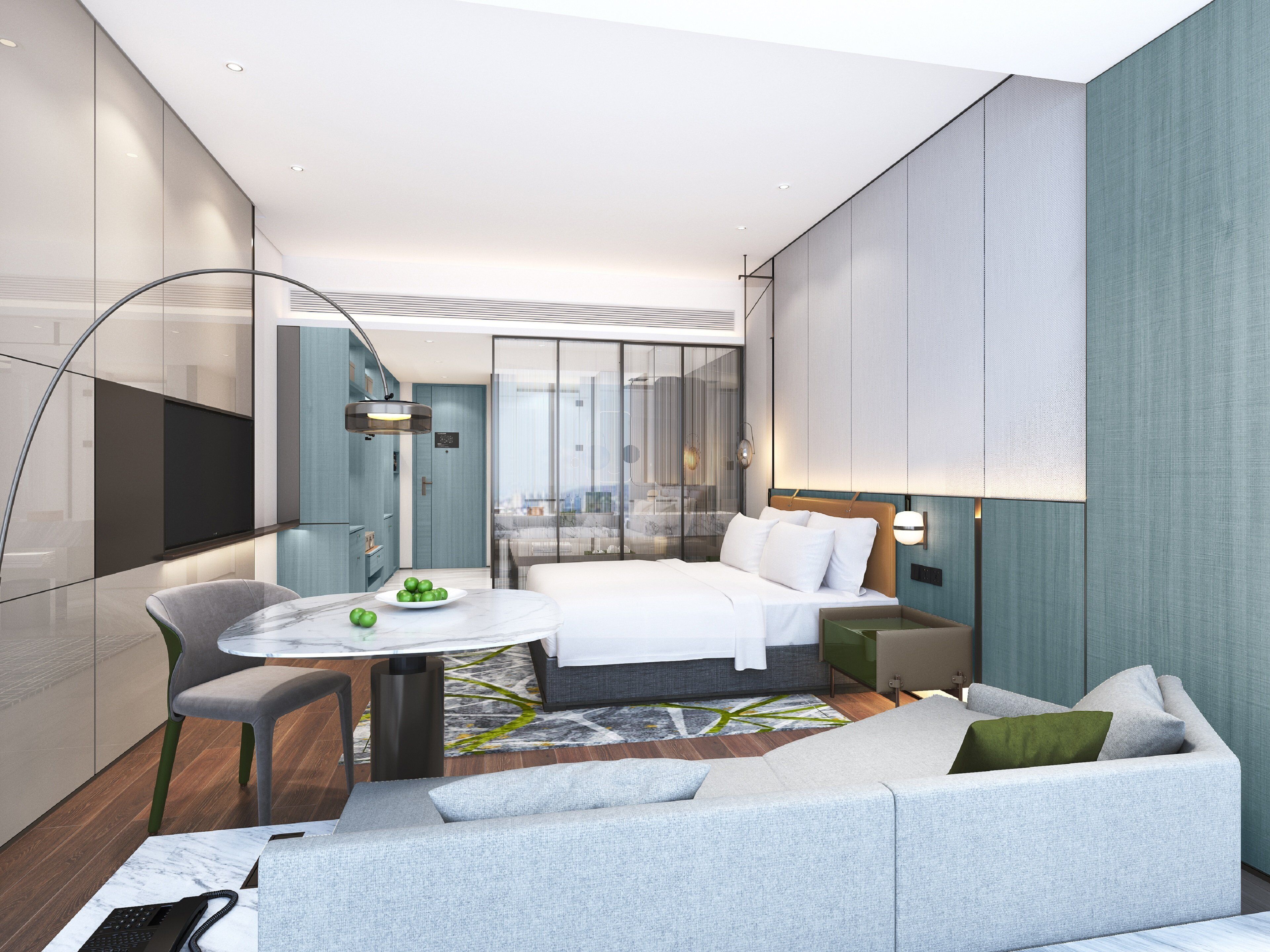 A modern hotel room with a bed, a seating area with a table and chairs, a desk with a computer, and a large window offering a city view.