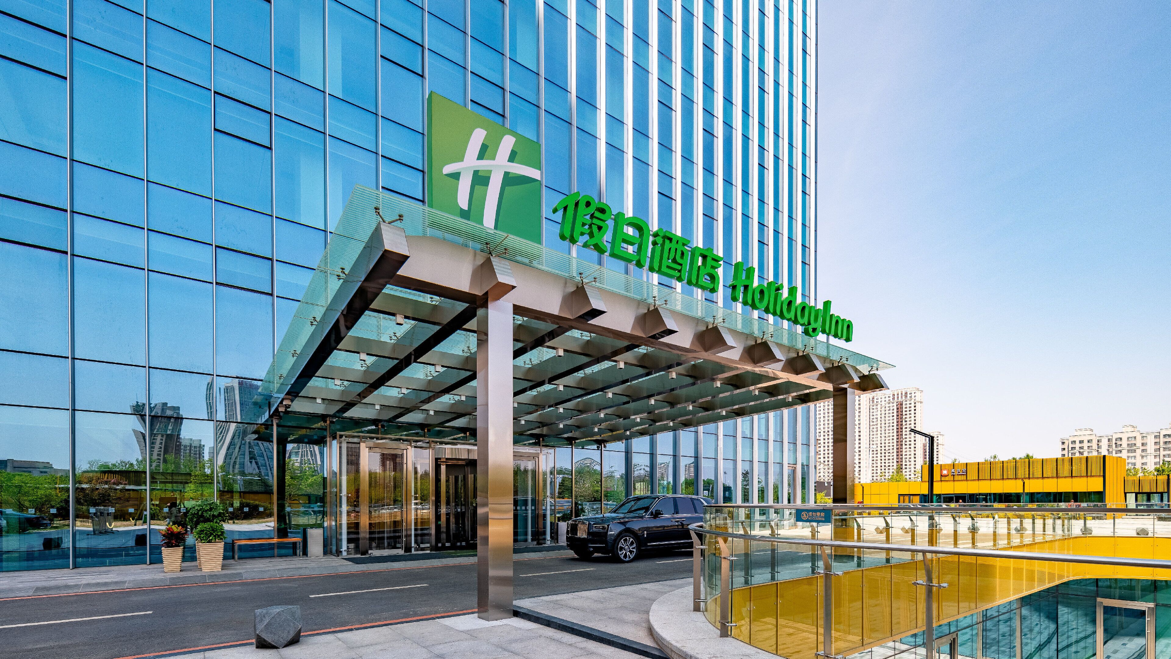 Un hotel moderno con fachada de vidrio y un letrero verde que indica que es un Holiday Inn.