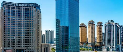 A modern high-rise building with a glass facade, surrounded by other tall buildings in an urban setting.