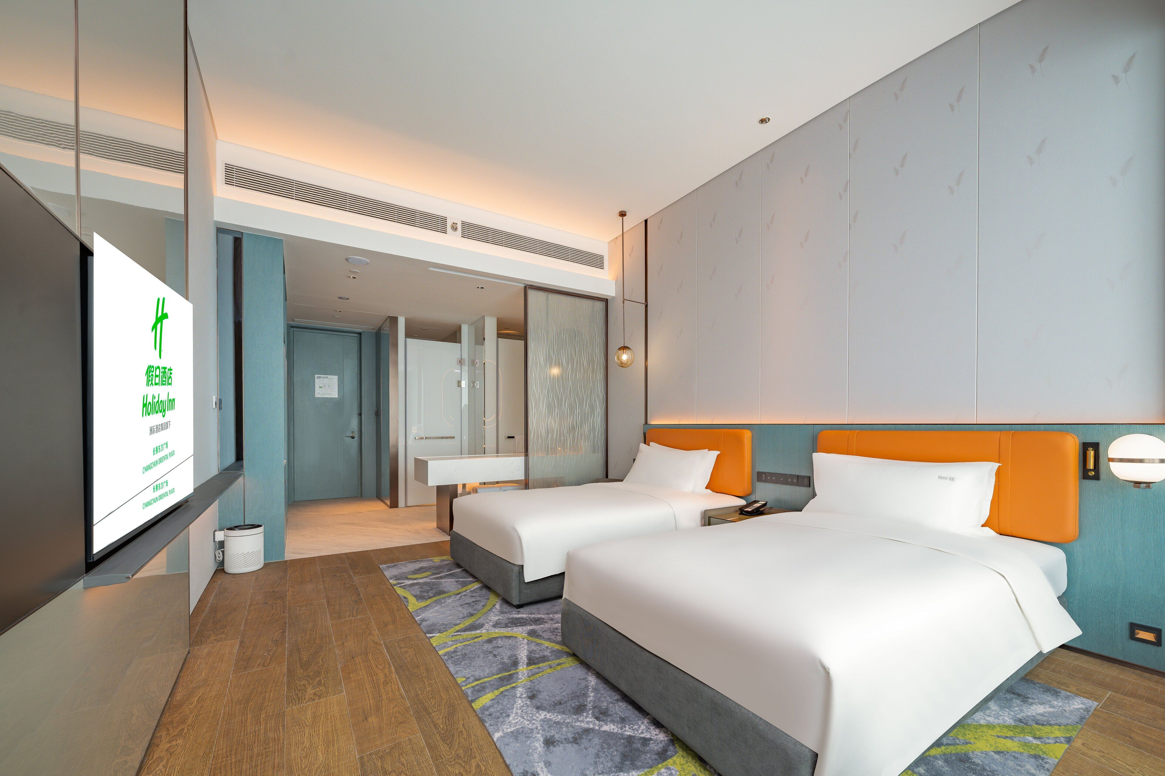 A hotel room with two beds, a large mirror, and a TV displaying a sign.