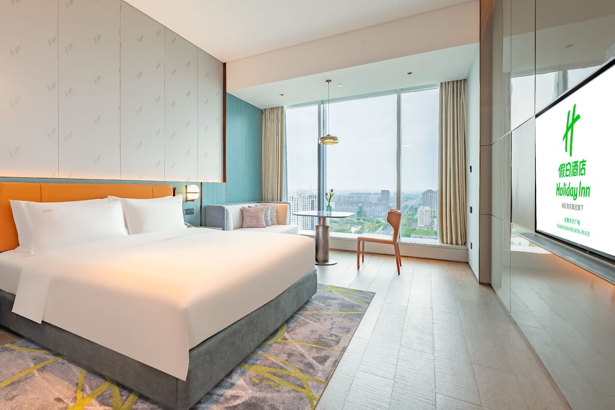 Een moderne hotelkamer met een groot bed, uitzicht op de stad en een balkon.