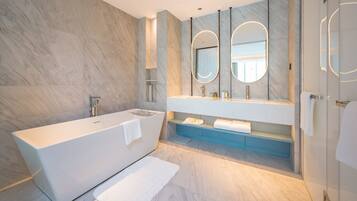 Un baño moderno con una bañera independiente, un espejo grande y un mueble de tocador empotrado.