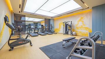 A modern gym with treadmills, elliptical machines, and free weights.