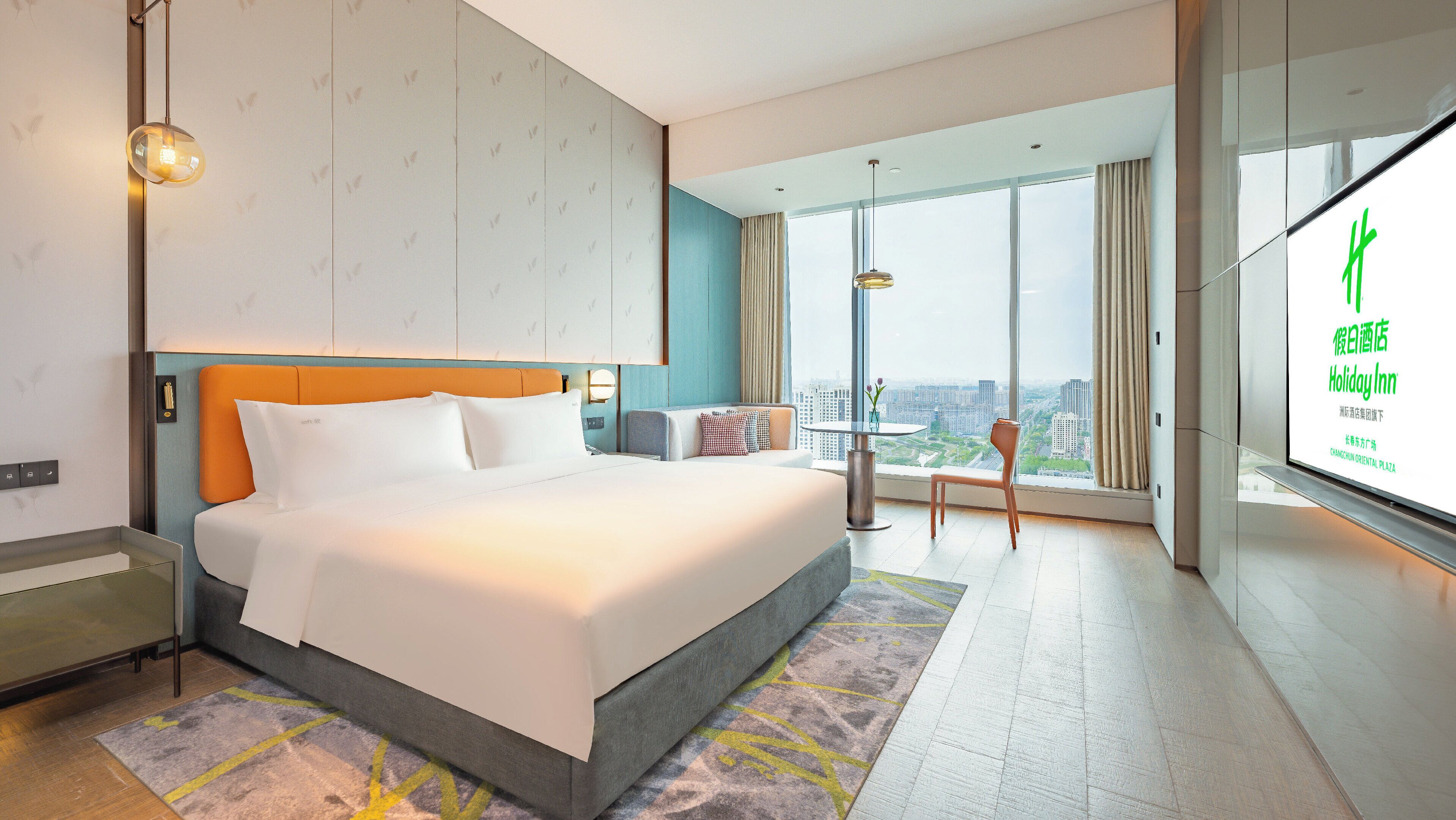 A modern hotel room with a large bed, a view of the city, and a balcony.