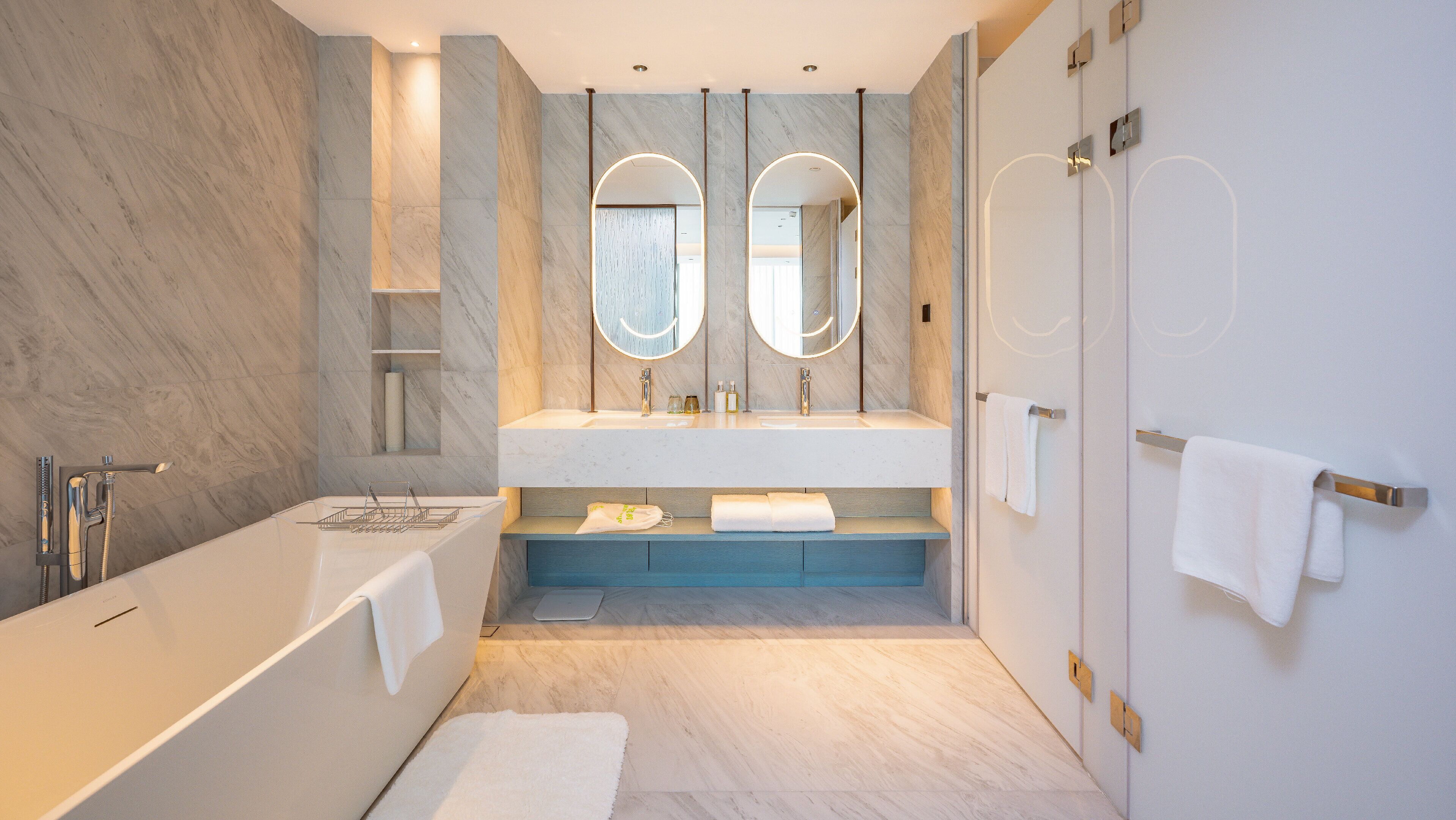 A modern bathroom with a large bathtub, a double sink with mirrors, and a shower area.