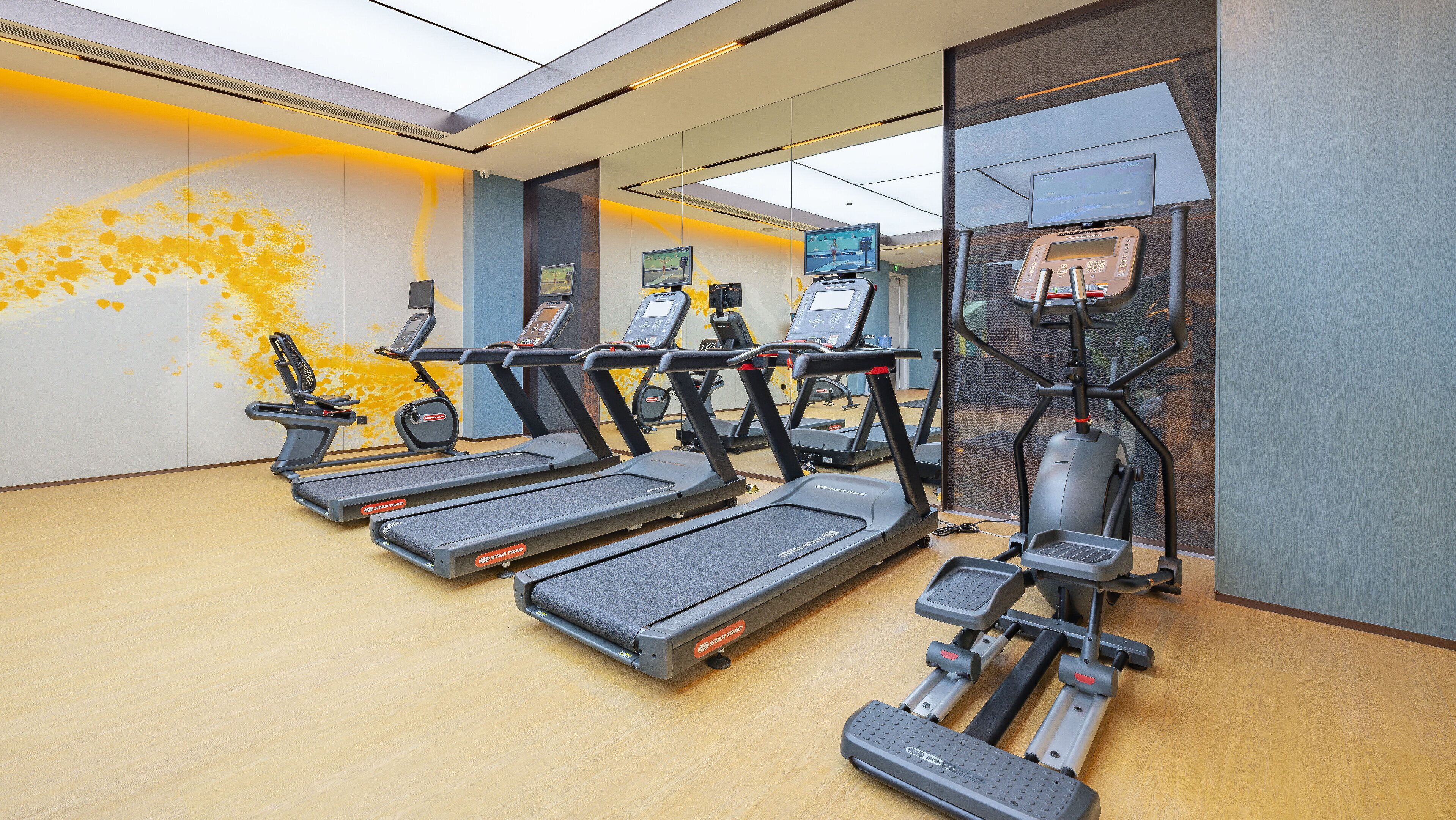 A gym with multiple treadmills, ellipticals, and a stationary bike.