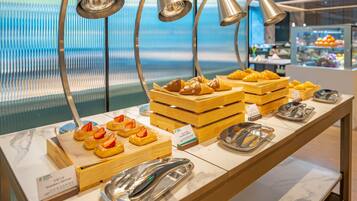 A buffet with pastries and strawberries, with a view of the sea in the background.