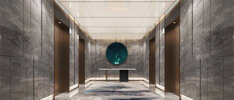 A modern interior with a central reception desk, marble walls, and a patterned carpet.