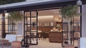 An open-plan living area with a sofa, dining table, and potted plants. - Salento Winery Lodge (Manduria)