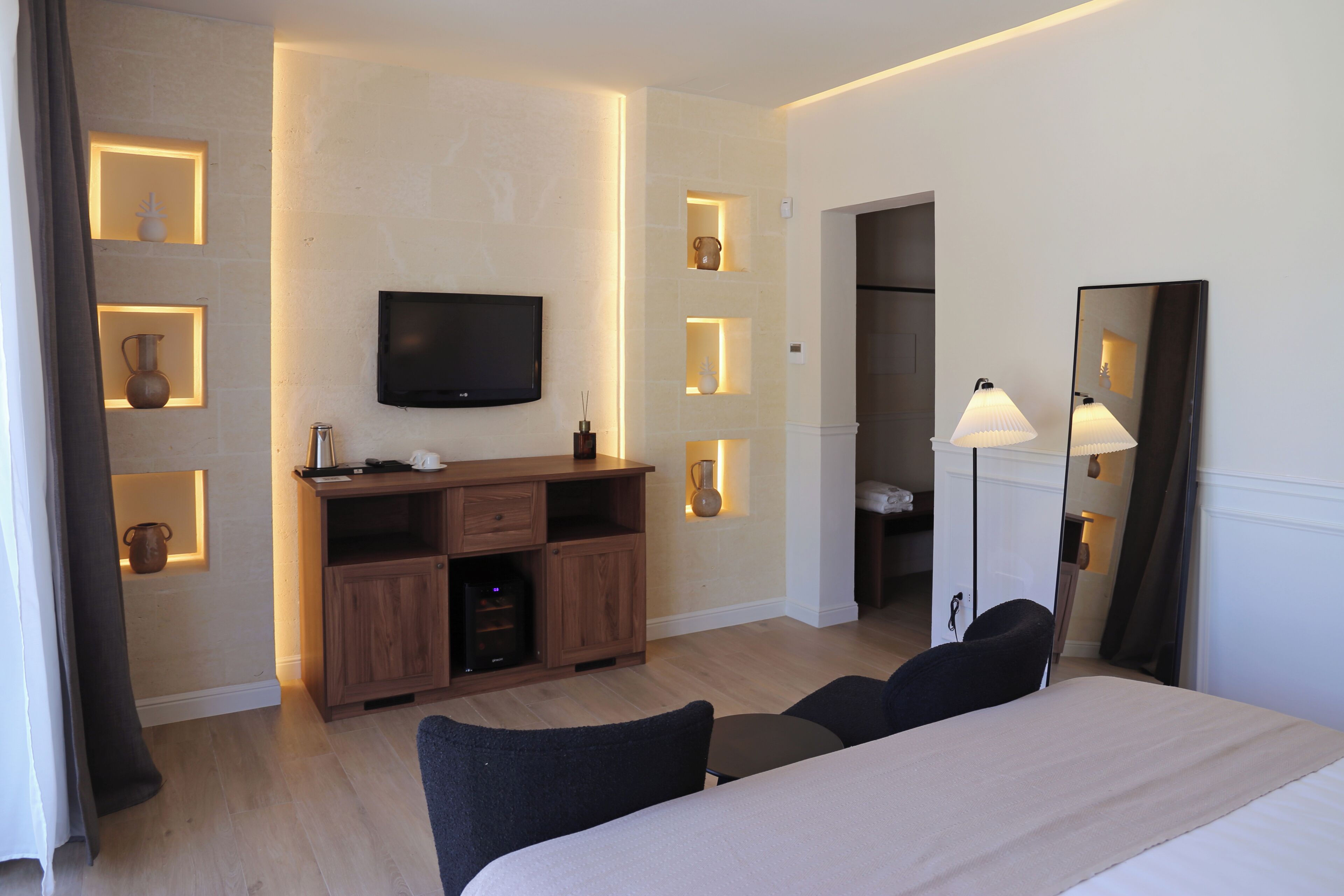 Ein Hotelzimmer mit Bett, Fernseher, Schreibtisch und Kleiderschrank.