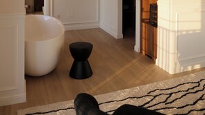 A modern living room with a large white bathtub, a black ottoman, and a wooden shelving unit. - Salento Winery Lodge (Manduria)