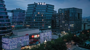 A modern hotel with a curved facade, multiple floors, and illuminated signage. - Ji Hotel Hangzhou Songcheng (Hangzhou)