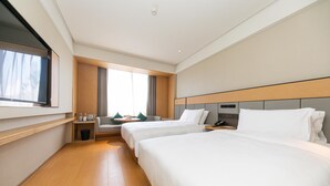 A hotel room with two beds, a TV, a window with curtains, a small table with a lamp, and a nightstand with a phone. - Ji Hotel Hangzhou Songcheng (Hangzhou)