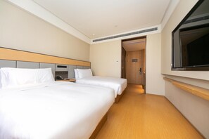 Una habitación de hotel con dos camas, un cabecero de madera, un espejo grande y suelo de madera.