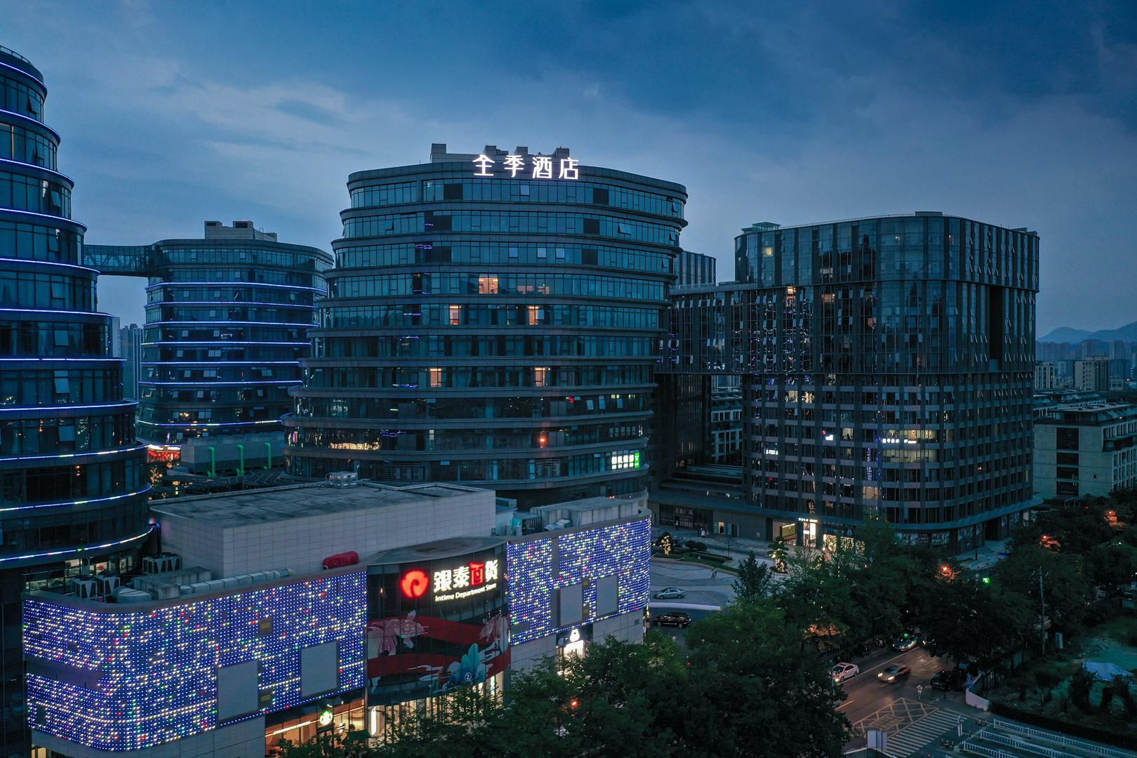 A modern hotel with a curved facade, multiple floors, and illuminated signage.