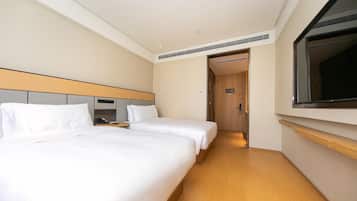 Una habitación de hotel con dos camas, un cabecero de madera, un espejo grande y suelo de madera.