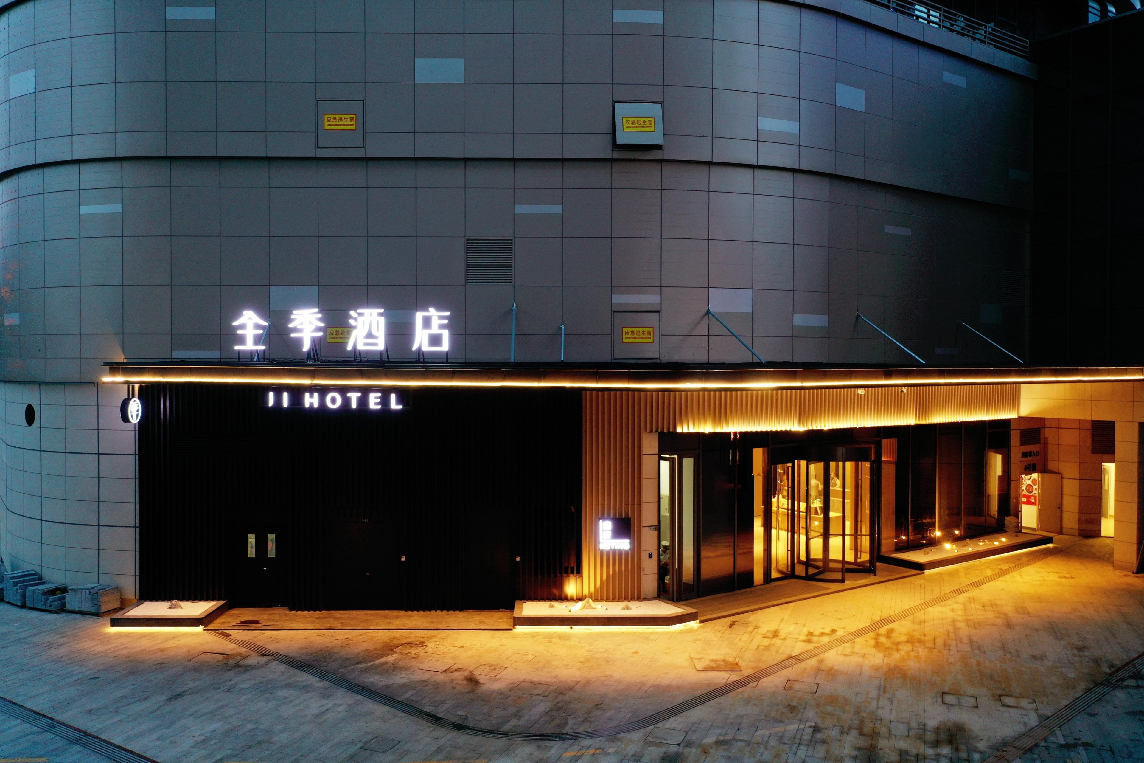 A hotel entrance with a modern design, featuring a prominent sign and a well-lit facade.