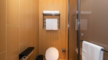 A bathroom with a toilet, a towel rack, and a trash bin.