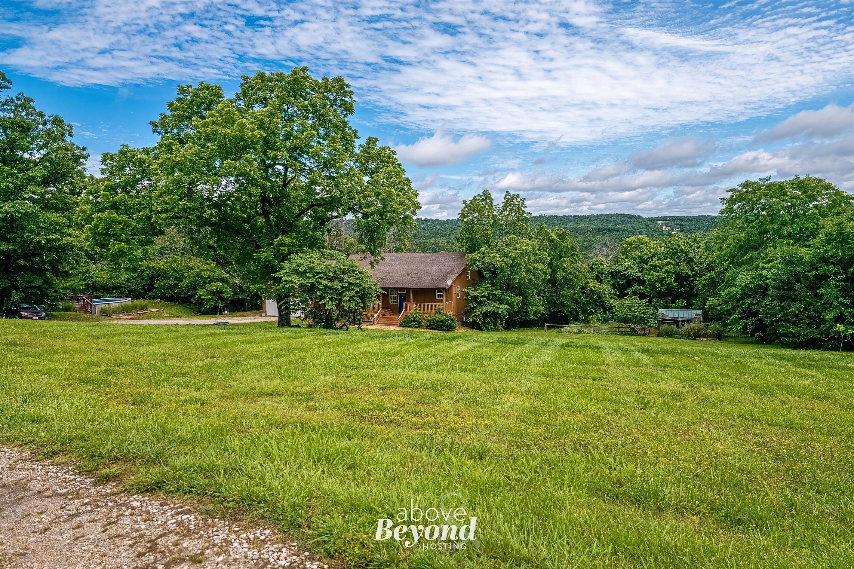 A rural landscape with a house surrounded by lush greenery and trees.
