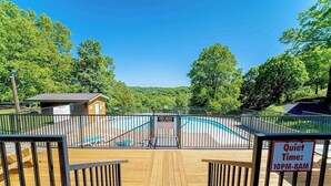 Ein Poolbereich mit Holzterrasse, einem eingezäunten Pool und einem Schild mit der Aufschrift 'Ruhezeit: 22 bis 8 Uhr.'